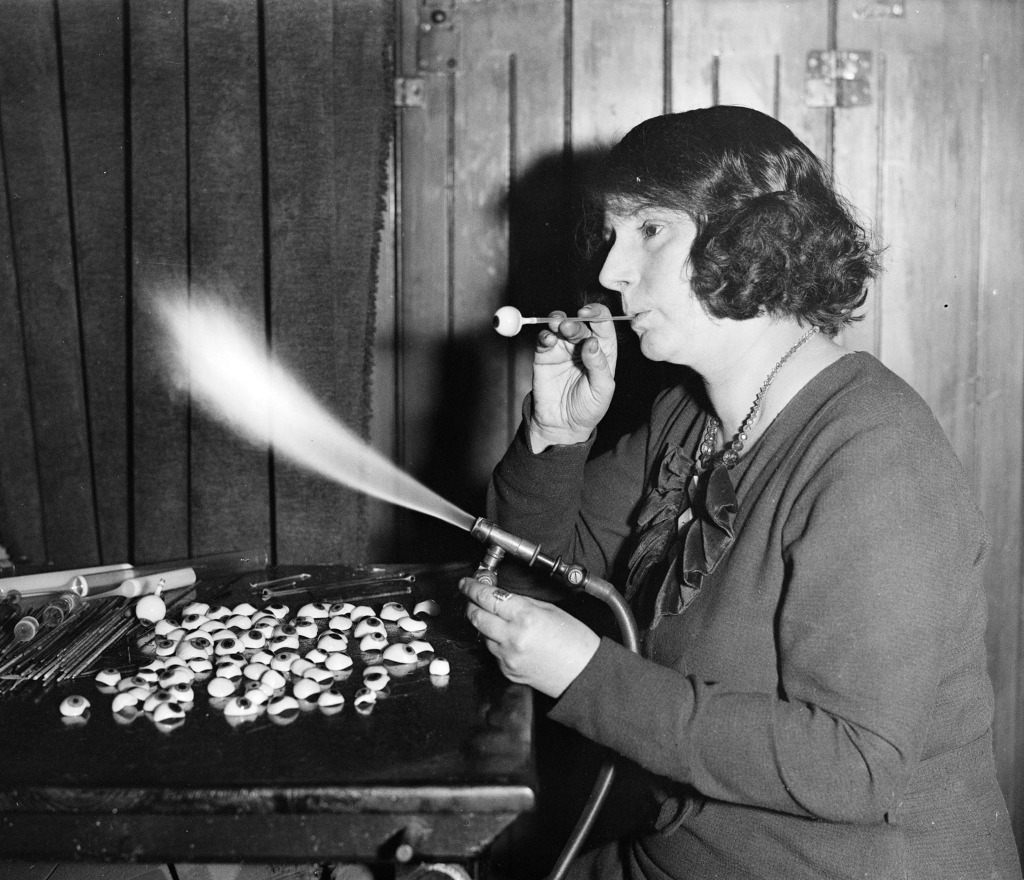 Woman making glass eyes, 1935 Black and white photograph of woman making glass eyes, holding blow torch